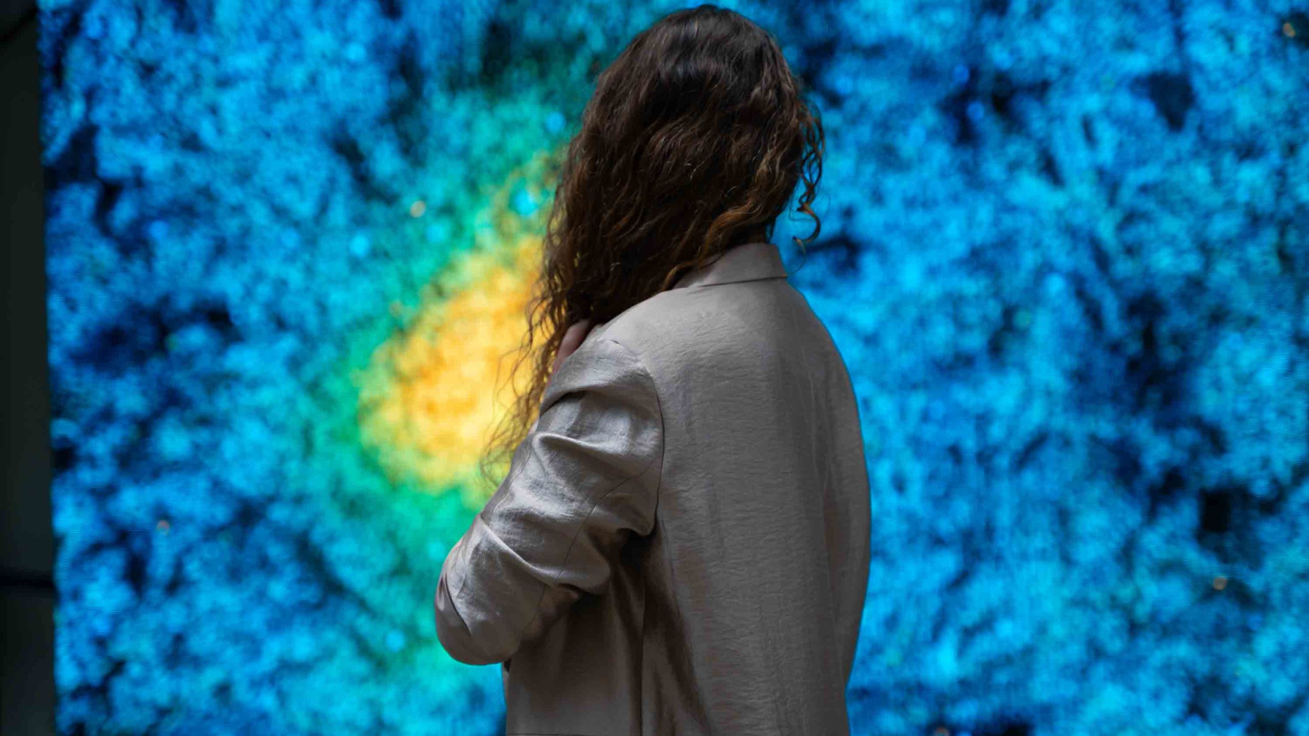 Frau vor golden blauer Videokunstinstallation
